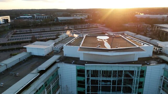 Aerial view of buildings and a parking lot, bathed in the warm glow of the sun, creating a striking contrast of light and shadow, Solihull, England, United Kingdom.