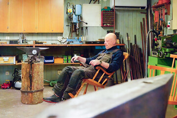 Quiet rest in workshop as an older man resting in workshop chair, calm moment between tasks- balanced work rhythm and sustainable activity in later life.