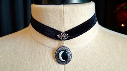 Black velvet choker with crescent moon pendant displayed on a mannequin in a studio setting