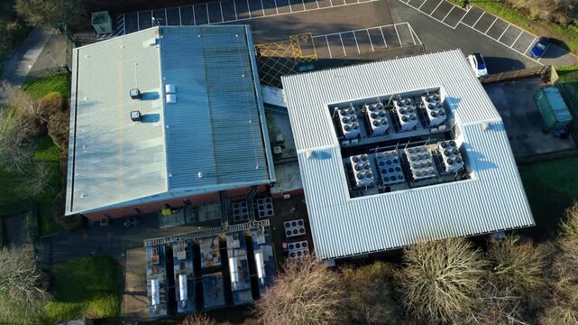 Aerial view of the industrial Six Degrees data centre with rows of air conditioning units, its metallic roof shining in the sunlight, Redditch, United Kingdom.