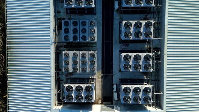 Aerial view of multiple air conditioning units adorn the rooftop, contrasting with the bare trees and the adjacent parking area, Redditch, United Kingdom.
