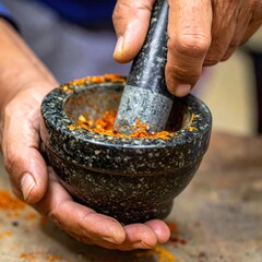 CloseUp Of Hands Grinding Spices In A Stone Mortar With Pestle Vibrant Orange Powder In Natural Light