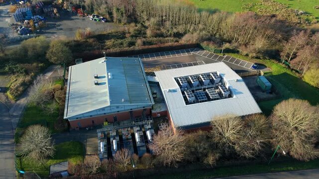 Aerial view of the Six Degrees data centre with metallic roofs and cooling units, surrounded by trees and a parking lot, Redditch, United Kingdom.