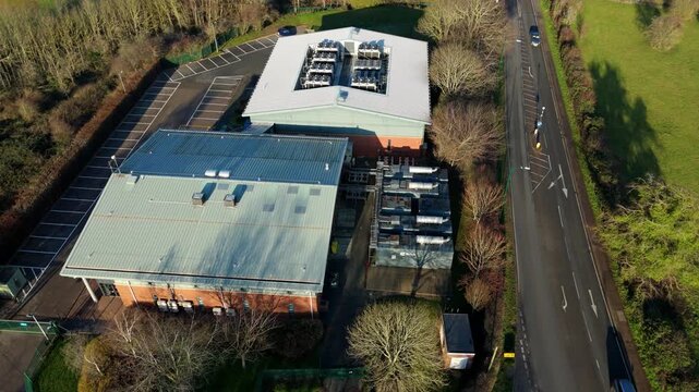 Aerial view of the Six Degrees data centre with its silver rooftops, parking lot, and adjacent road cutting through the landscape, Redditch, United Kingdom.