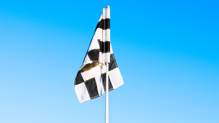 Golf flag waving in the blue sky over a luxury golf course during a sunny day