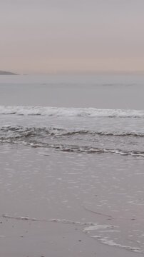 EDINBURGH, SCOTLAND, UK - JANUARY 5, 2024: Tranquil atmosphere of Portobello Beach in Edinburgh as clouds soften the sunrise over gentle waves, bringing peace to the coast, island in the mist on the