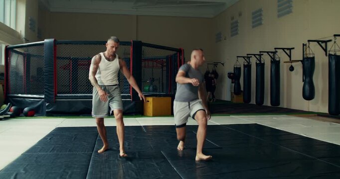 Men perform warm-up exercises before MMA training..