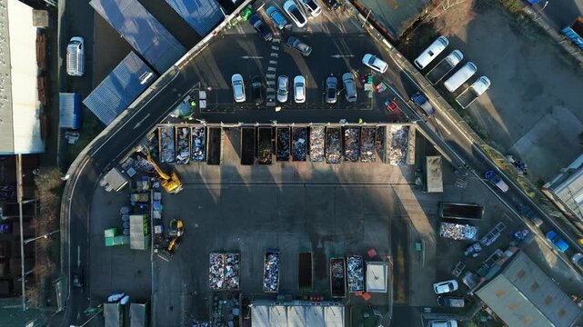 Aerial view of a bustling waste management site with rows of containers filled with colorful waste, machinery, and vehicles, Rugby, England, United Kingdom.