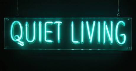 Bright neon sign displays words quiet living. Dark background emphasizes glowing turquoise illumination. Simple, modern aesthetic.
