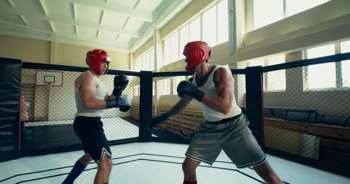 One of the mixed martial artists lands offensive strikes on his opponent and knocks him down. Two MMA fighters spar in the ring.