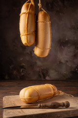 Provolone cheese, wonderful smoked provolone cheese on rustic wood and accessories, abstract background, selective focus.