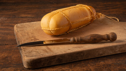 Provolone cheese, wonderful smoked provolone cheese on rustic wood and accessories, abstract background, selective focus.