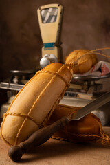 Provolone cheese, wonderful smoked provolone cheese on rustic wood and accessories, abstract background, selective focus.