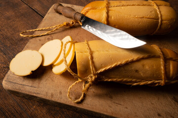 Provolone cheese, wonderful smoked provolone cheese on rustic wood and accessories, abstract background, selective focus.