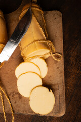 Provolone cheese, wonderful smoked provolone cheese on rustic wood and accessories, abstract background, selective focus.