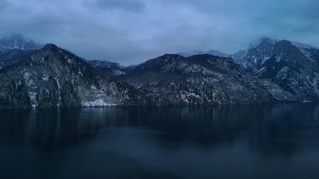 Aerial drone flying backward over alpine mountain range near Traunsee lake, Austria