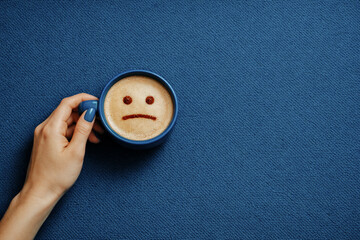 a sad face in a blue cup of coffee