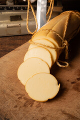 Provolone cheese, wonderful smoked provolone cheese on rustic wood and accessories, abstract background, selective focus.