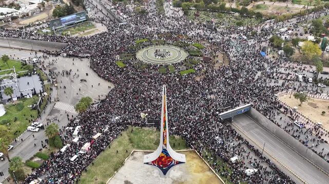 An aerial view of thousands of Syrians celebrating the end of the war in Damascus, carrying Syrian flags