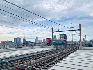 Fototapeta premium A wide-angle, high-angle view of elevated commuter railway tracks stretching into the distance towards a modern urban skyline.