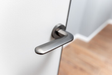 A silver door handle is shown in a mirror