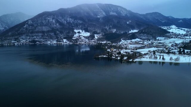 Aerial drone flying forward along lakeshore with mountain landscape over alpine lake Traunsee Austria
