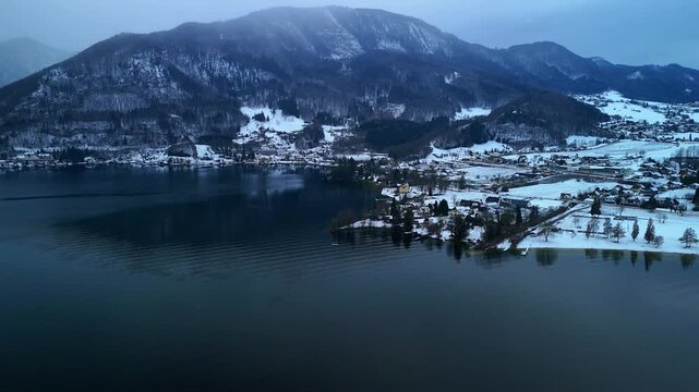 Aerial drone view of snowy mountain shoreline at Traunsee lake, Austria