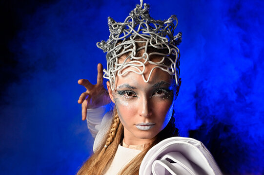 Colorful portrait of a girl dressed as the Snow Queen against a blue hazy background.