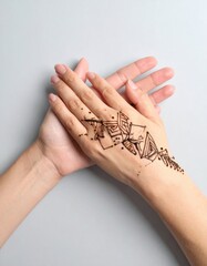 Close Up Of A Woman S Hands With Intricate Henna Tattoo Design On One Hand Against A Soft Grey Background Showing Delicate Skin Texture And Natural Lighting