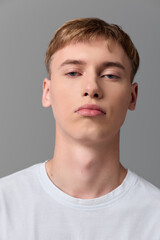 Fototapeta premium Man, young, face, white tshirt, neutral background, studio lighting, close up headshot with calm expression, minimal clean style for stock photography and versatile use in fashion and branding