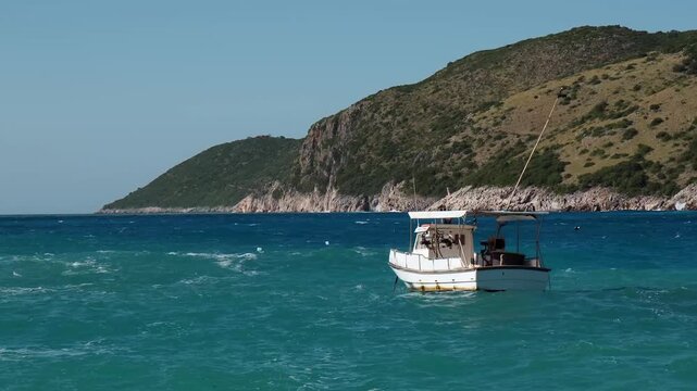 Boot auf t&uuml;rkisfarbenem Meer mit Wellen und K&uuml;ste, Jala, Qark Vlora, Albanien