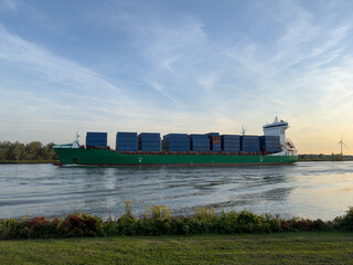 Containerschiff auf ruhigem Fluss bei Sonnenuntergang