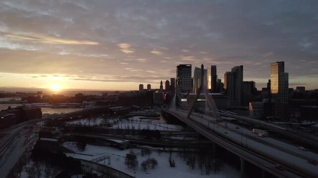 Boston, United States - 24 December 2025: Aerial view of the Leonard P. Zakim Bunker Hill Memorial Bridge at sunrise, towering over the snowy landscape.