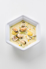 Creamy seafood chowder with mussels and corn in a white bowl © EdienuFoto
