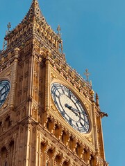 A detailed close-up of Big Ben shows the magnificent clock face with golden ornaments and Neo-Gothic architecture against a clear sky.