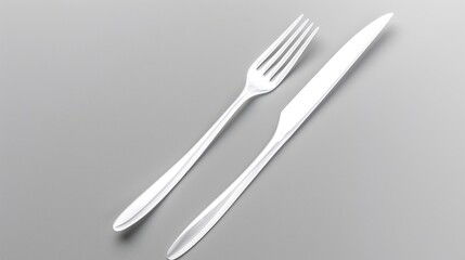 Shiny silver fork and knife set on a clean gray background, ready for dining.