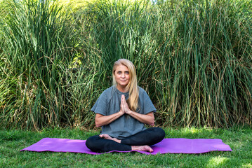 Peaceful lady in sportswear performing a zen meditation routine in nature