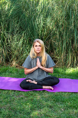 Active woman finding inner peace while meditating on a purple mat outdoors