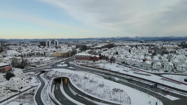 Aerial drone footage showing vehicle traffic moving through an urban area in Stavanger, Norway during winter. The scene captures roads, surrounding buildings, and typical city infrastructure under col