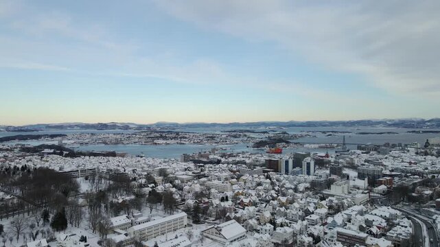 Aerial drone footage showing an urban neighborhood in Stavanger, Norway covered in snow during winter. The scene includes residential buildings, streets, and surrounding infrastructure, documenting ty