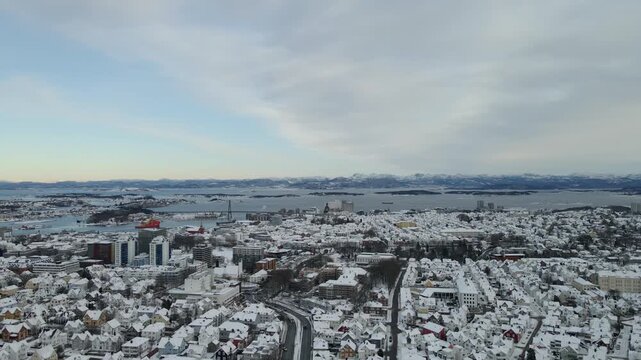 Aerial drone footage showing an urban neighborhood in Stavanger, Norway covered in snow during winter. The scene includes residential buildings, streets, and surrounding infrastructure, documenting ty