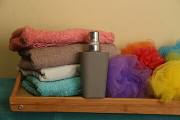 Towels and wash items displayed on a wooden tray in a bathroom setting with a bottle and loofahs
