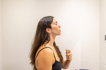 Woman applying beauty product, spraying fragrance on neck, completing personal care routine