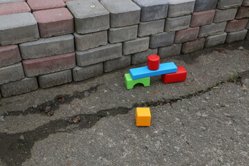 Colorful blocks arranged near a wall made of bricks on a concrete surface in daylight