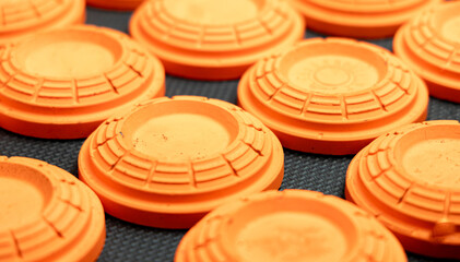 orange clay targets laid out on a black table, background of patterns