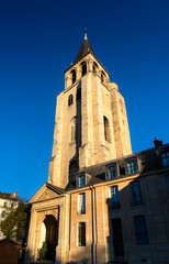 Church of Saint-Germain-des-Pres stands in the 6th district of Paris, France. Historic Romanesque architecture features the stone bell tower and abbey buildings under a blue sky