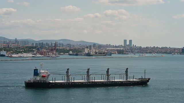 Istanbul, turkey, august 1, 2025. A large, empty dry cargo ship navigating the waters of the bosphorus strait, with the modern skyline of istanbul, turkey, in the background
