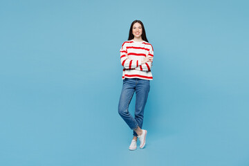 Full body young smiling happy woman wear red striped sweatshirt casual clothes hold hands crossed folded look camera isolated on plain pastel light blue background studio portrait. Lifestyle concept.