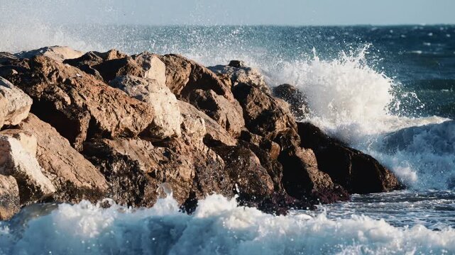 Close up of ocean waves breaking against large coastal rocks