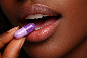 Woman taking purple capsule supplement close up